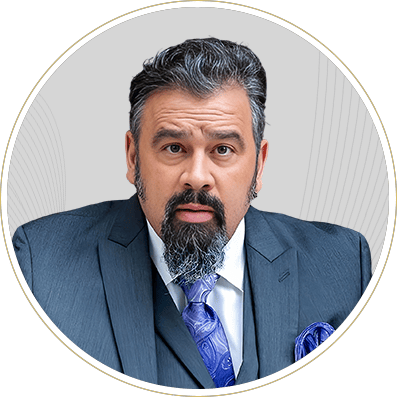 Formal portrait of a man in a blue suit and tie, with a salt-and-pepper beard, against a light gray background