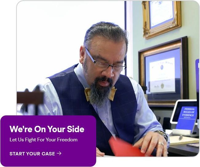 Attorney reviewing paperwork at a desk with a “We’re On Your Side” legal aid banner.