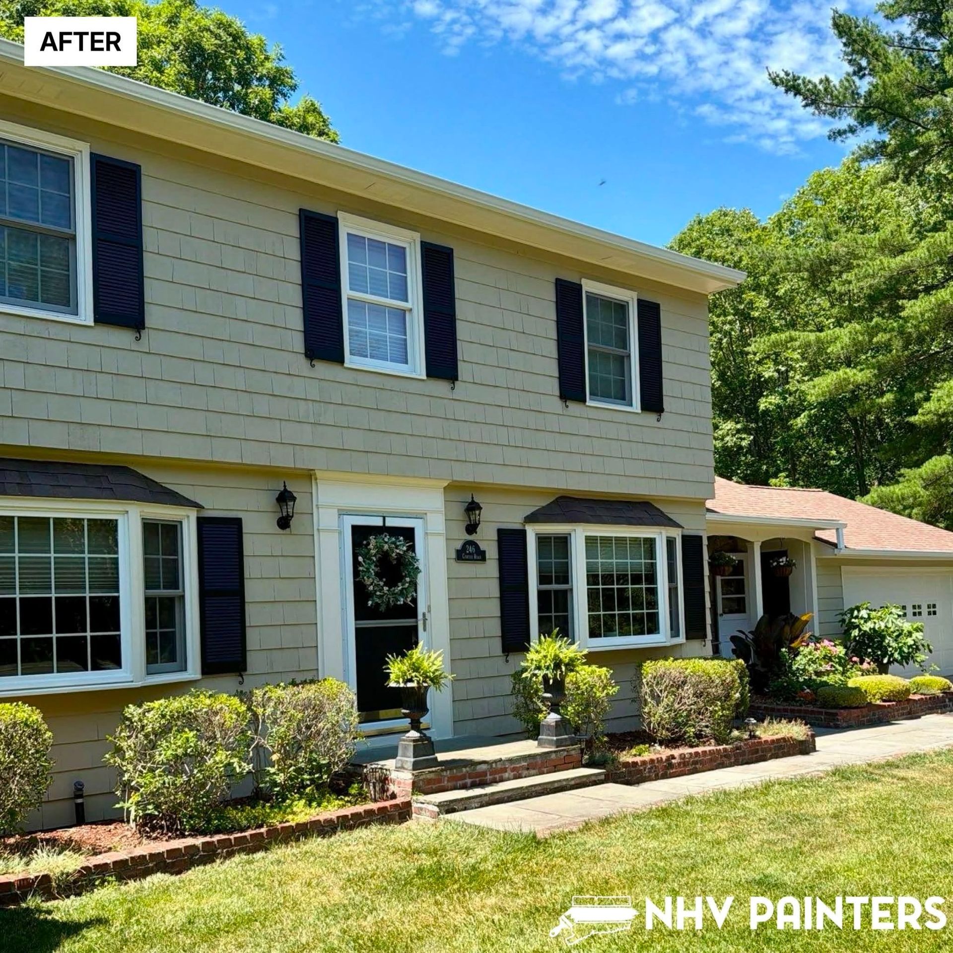 Two-story beige house with black shutters and white trim after exterior painting, sunny front yard.