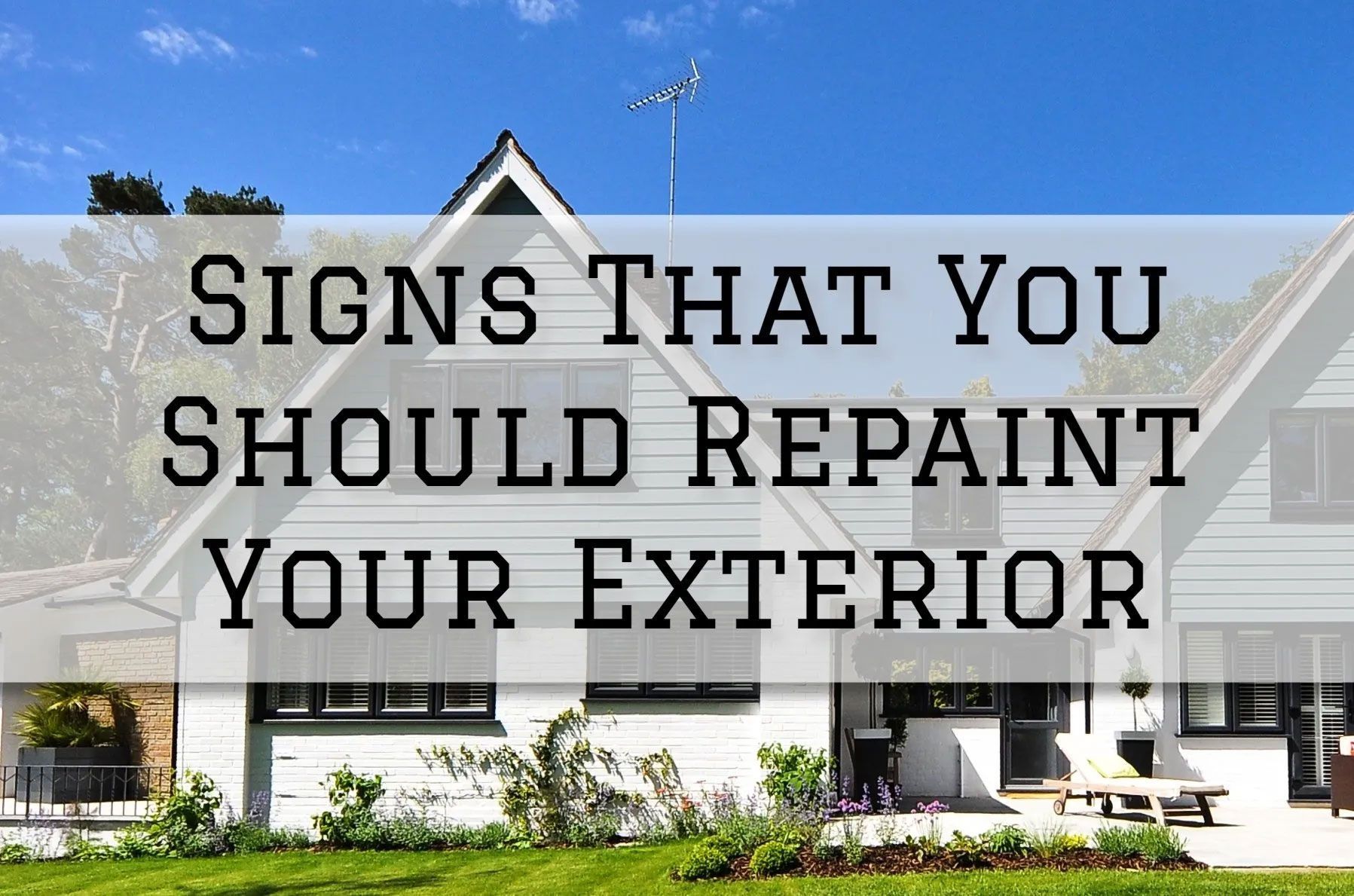 White house exterior with text overlay: Signs That You Should Repaint Your Exterior. Blue sky, green grass.