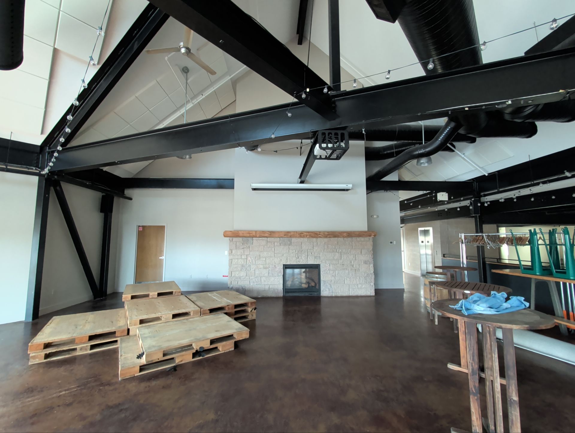 Spacious interior with exposed beams, fireplace, and wood pallets.