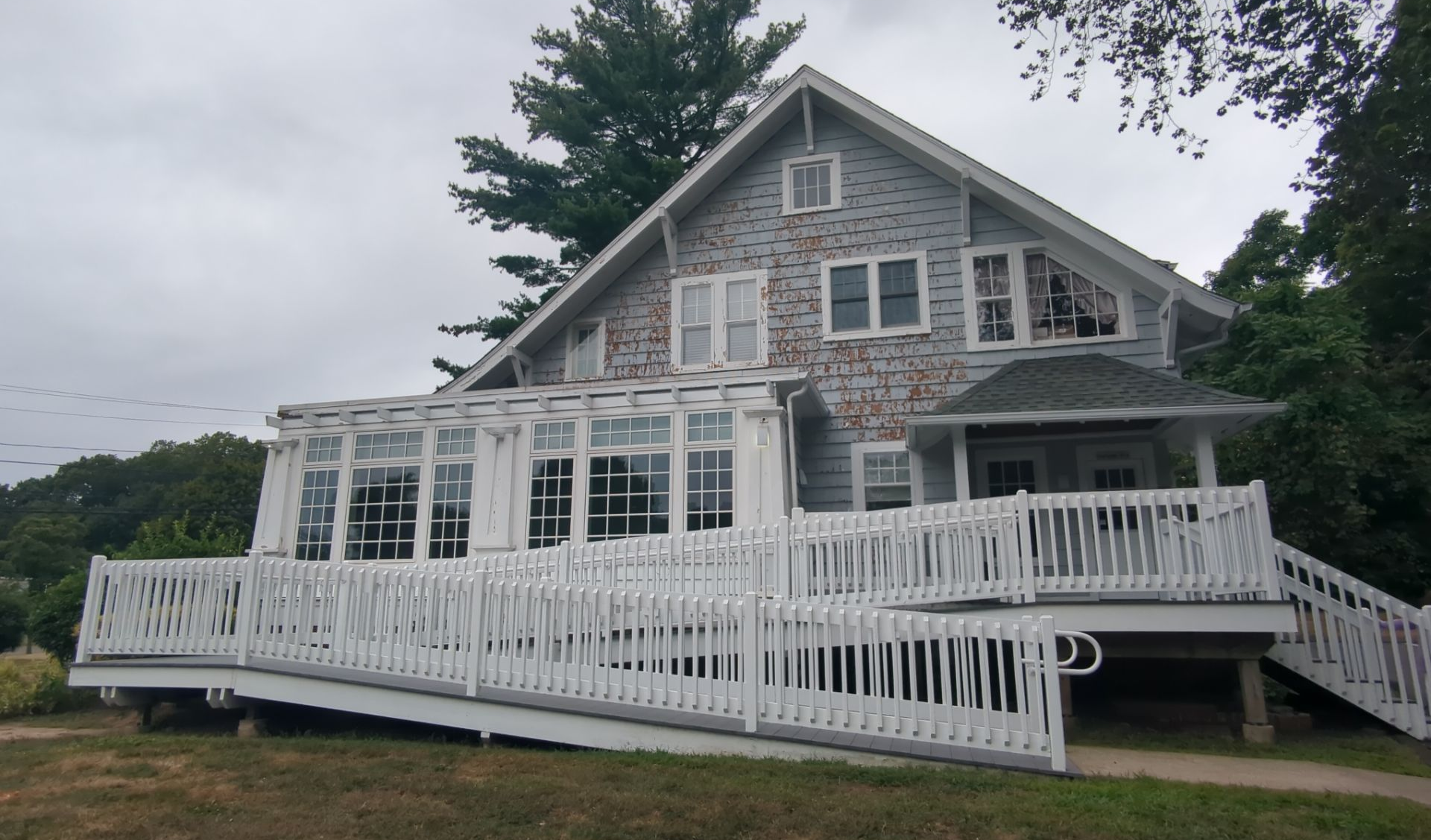 White house with porch and ramp on overcast day.