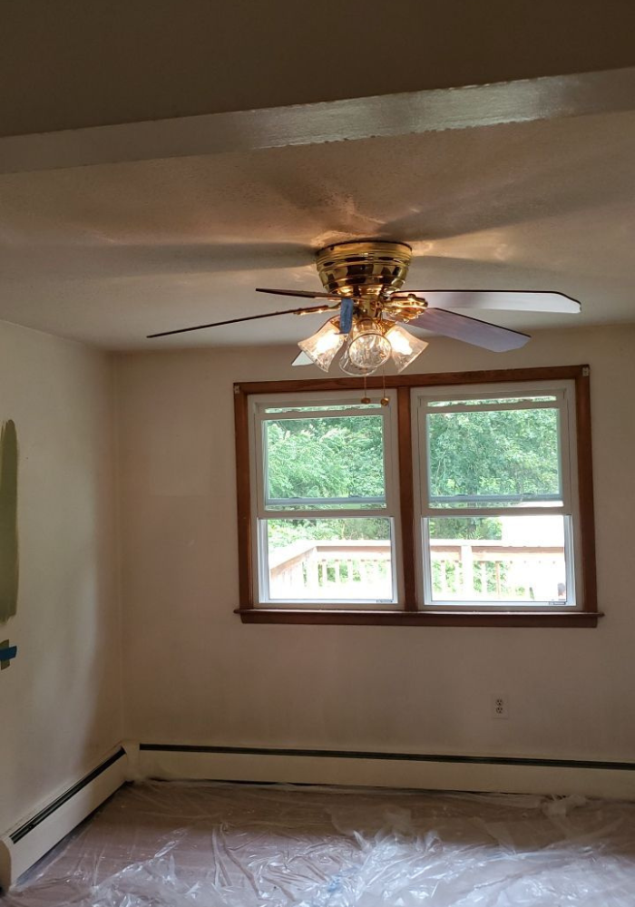 An empty room with a ceiling fan and a window