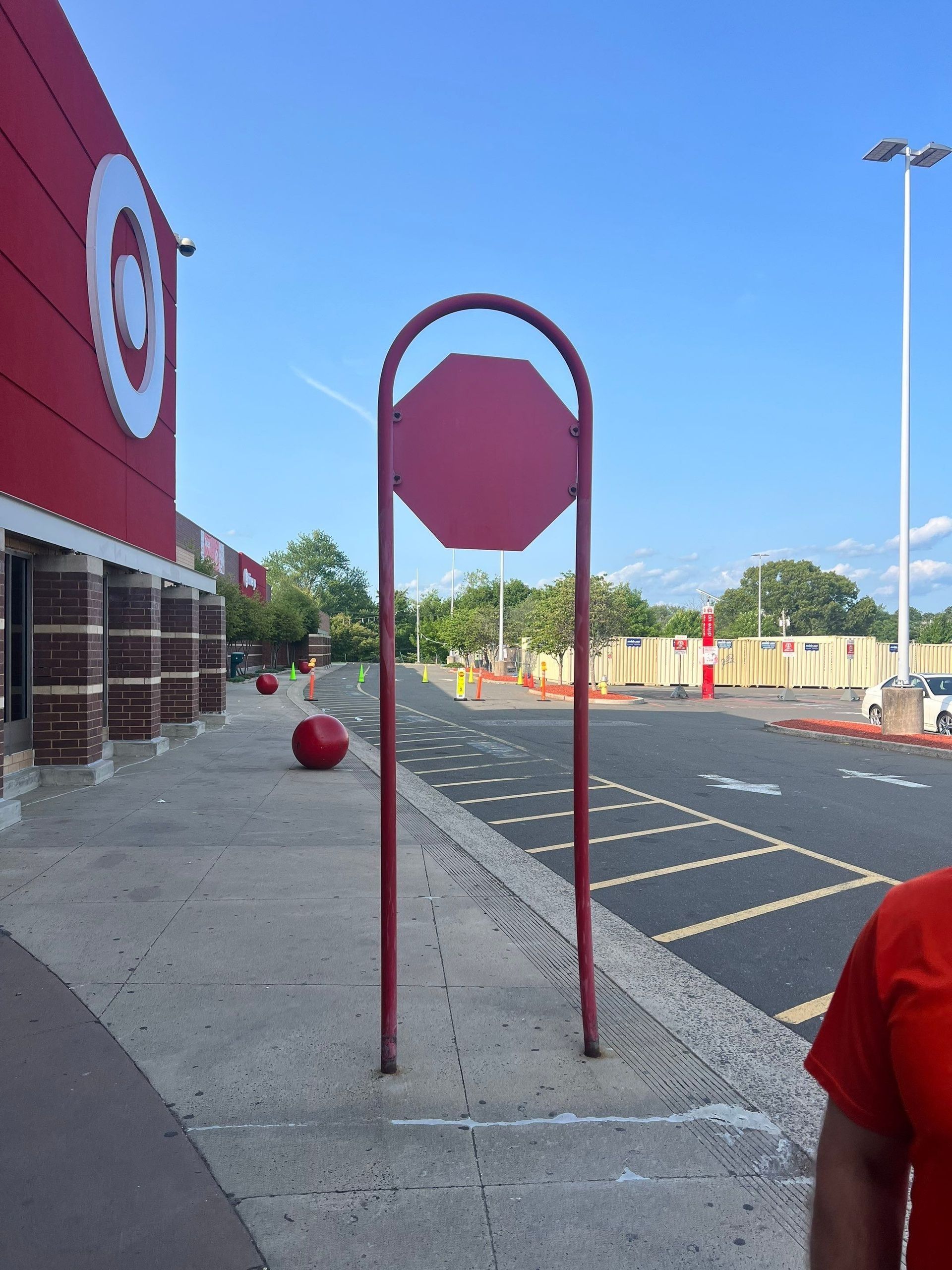 Outside a Target store, a red frame holds a blank octagon sign, with red spheres and a portion of a person in a red shirt visible.