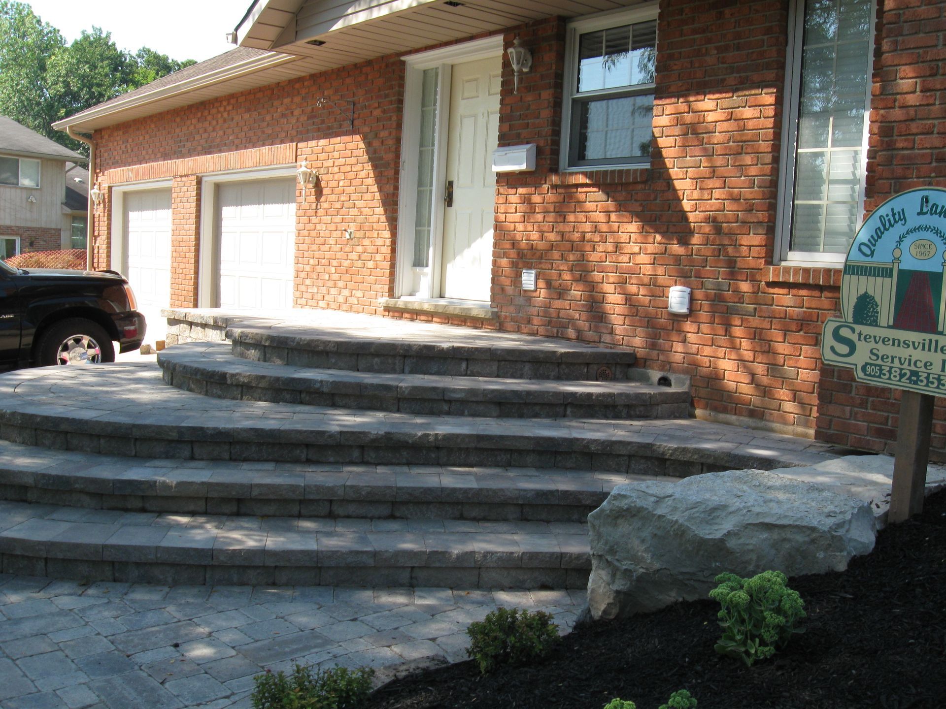 Brick house exterior with a multi-tiered curved stone staircase leading to a front entryway.