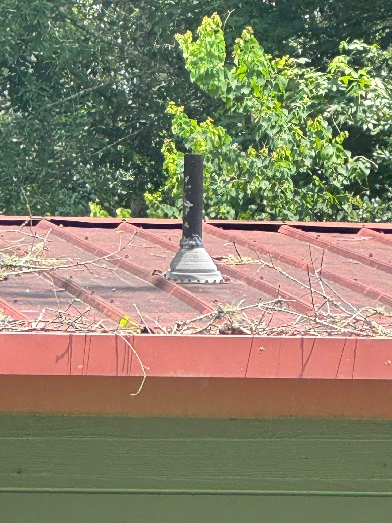 A red roof with a black chimney on top of it.