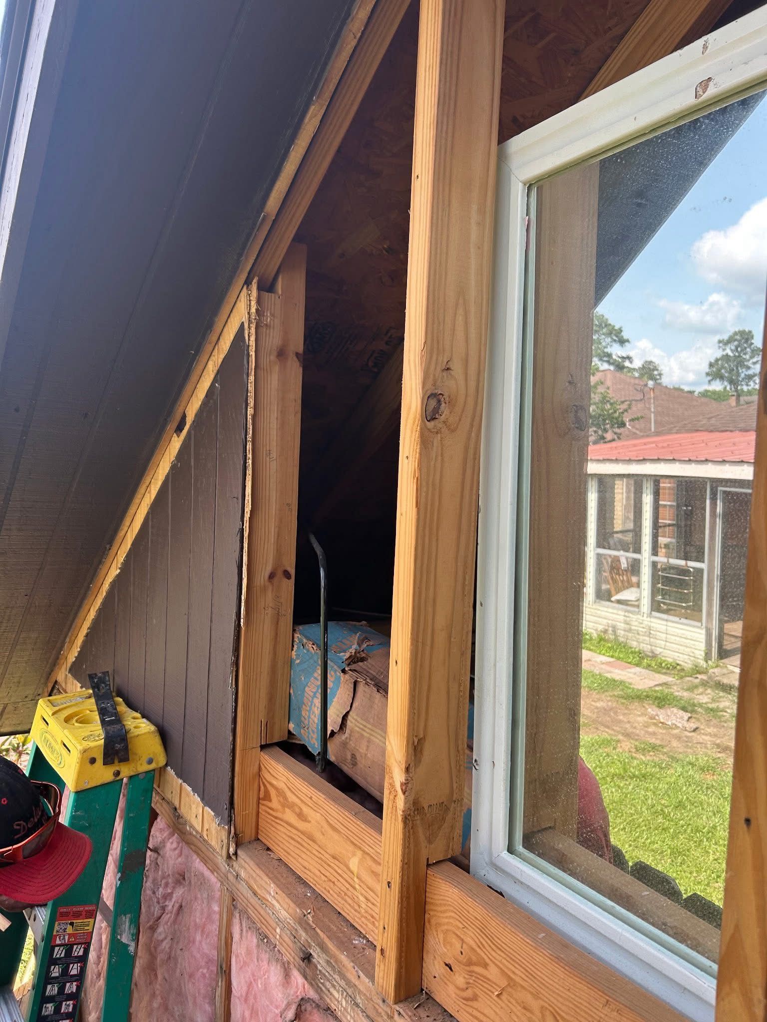 A window is being installed in the attic of a house.