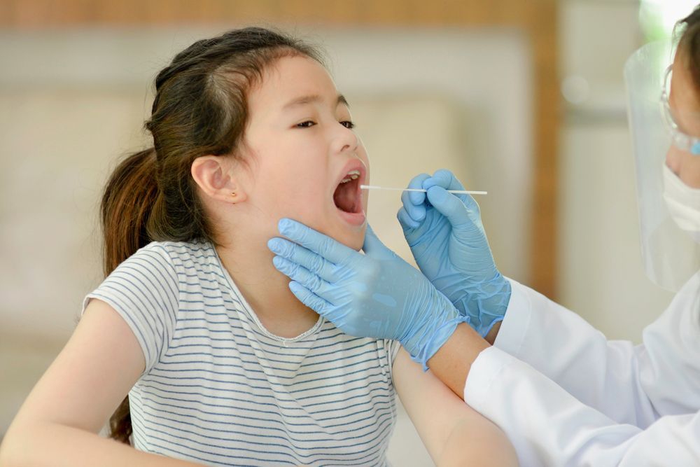 Dental professional examining a child’s open mouth with gloved hands in a clinic setting