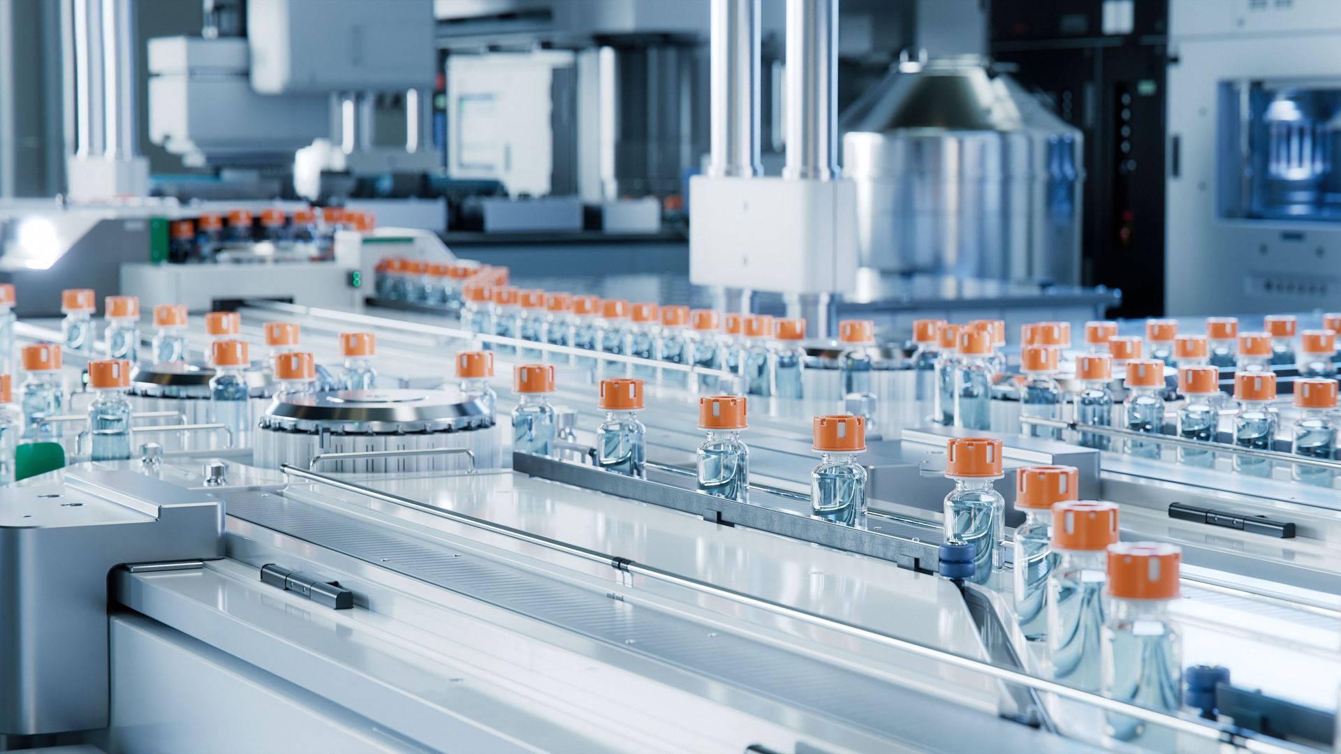 Rows of clear bottles with orange caps moving through an automated factory conveyor line.