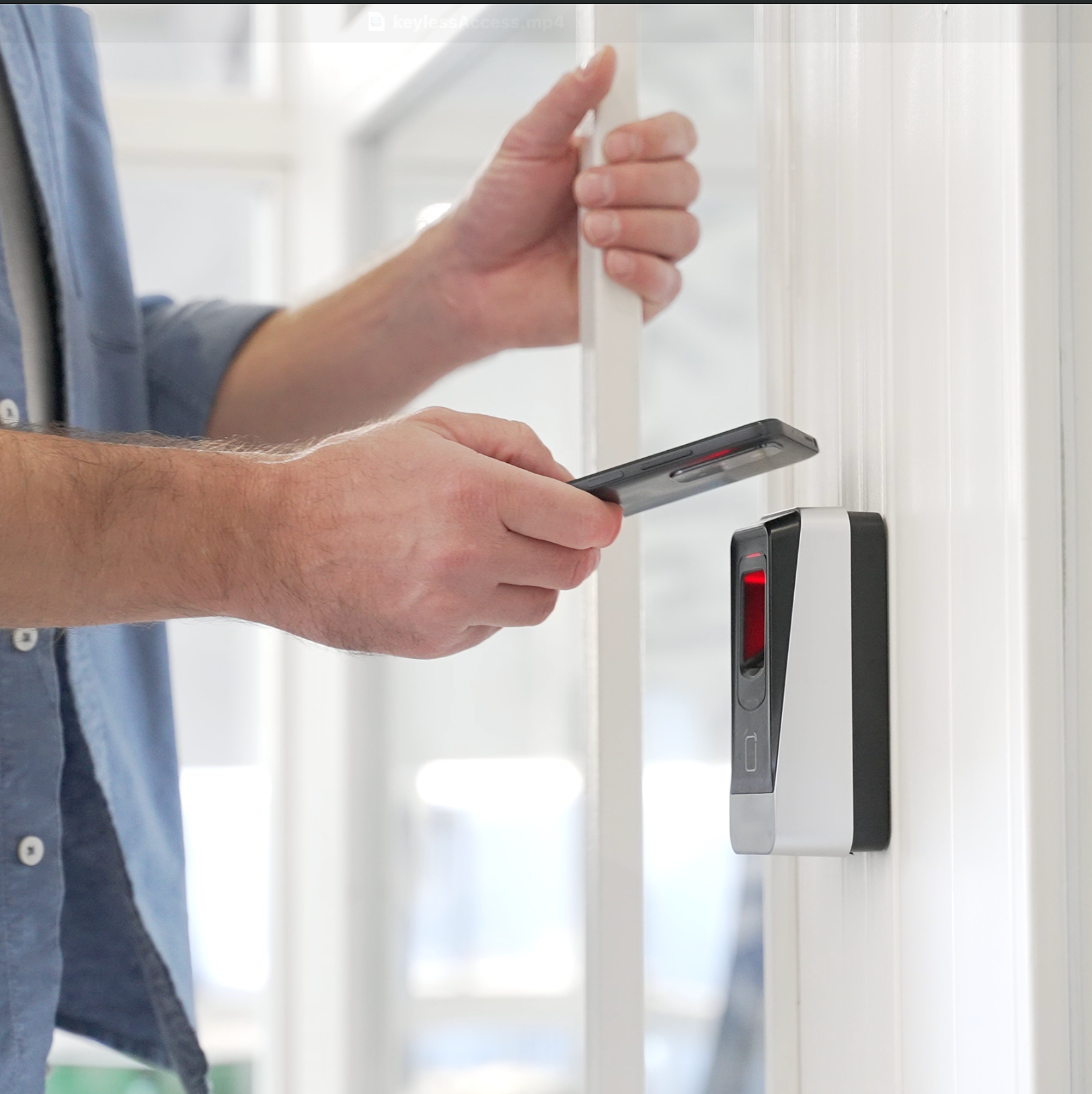 A man is using his phone to unlock a door with keyless access for businesses in Kansas.