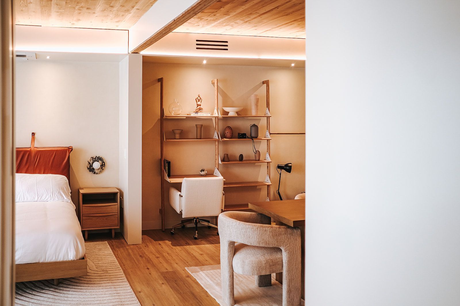 Cozy bedroom with wooden shelves, a bed, desk, and warm lighting in a modern rustic interior