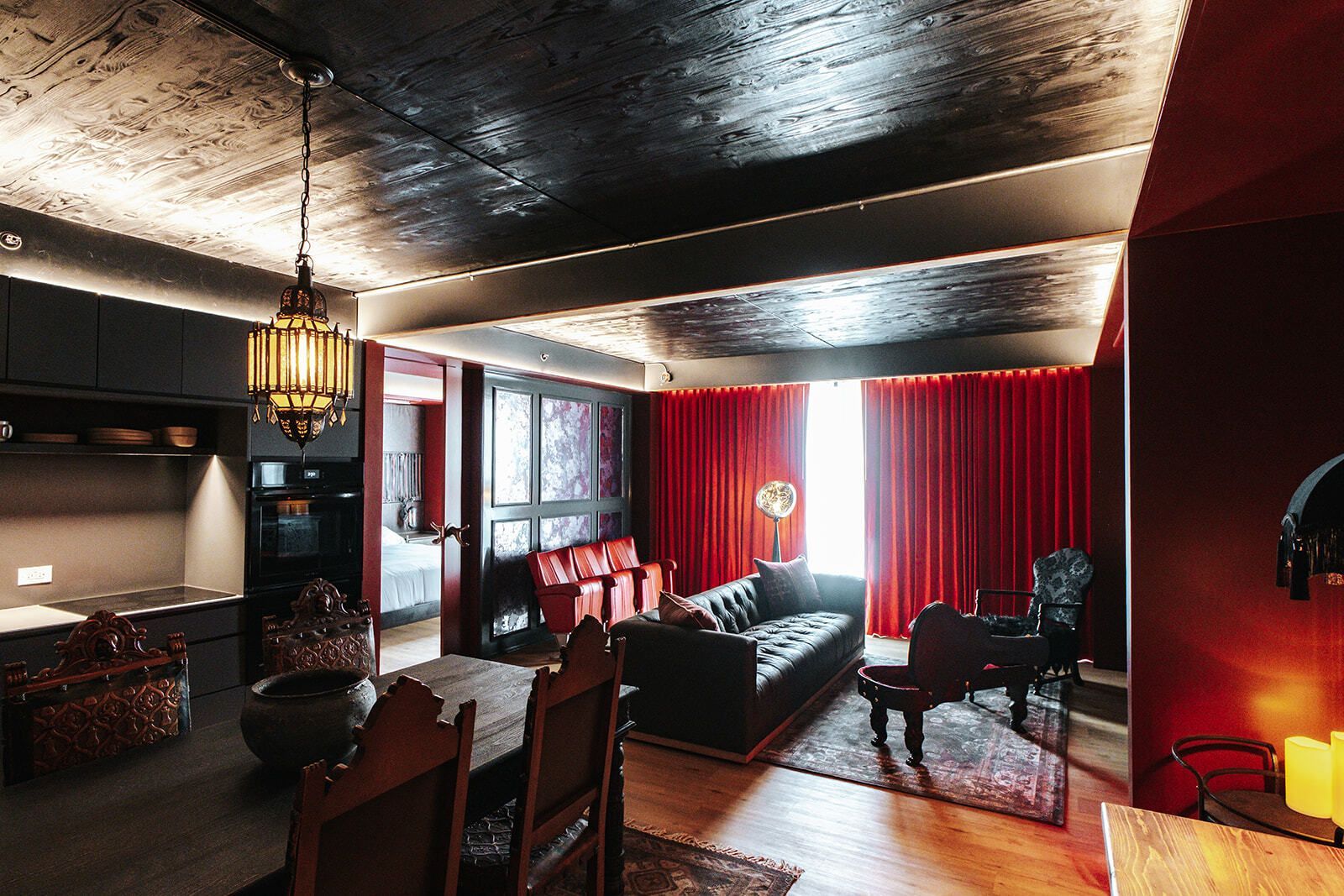 Dim red-and-black dining room with a small table, chairs, and ornate decor.