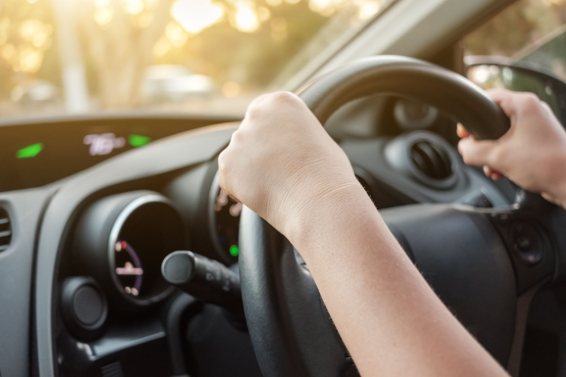 person with hands on the wheel driving a car