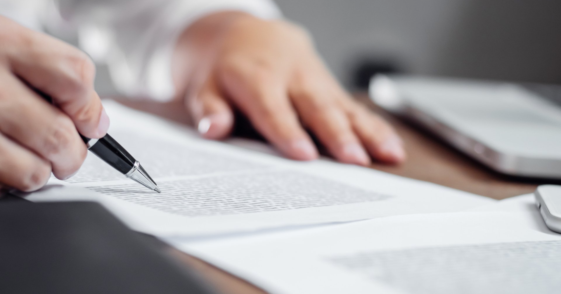 A person is signing a document with a pen.