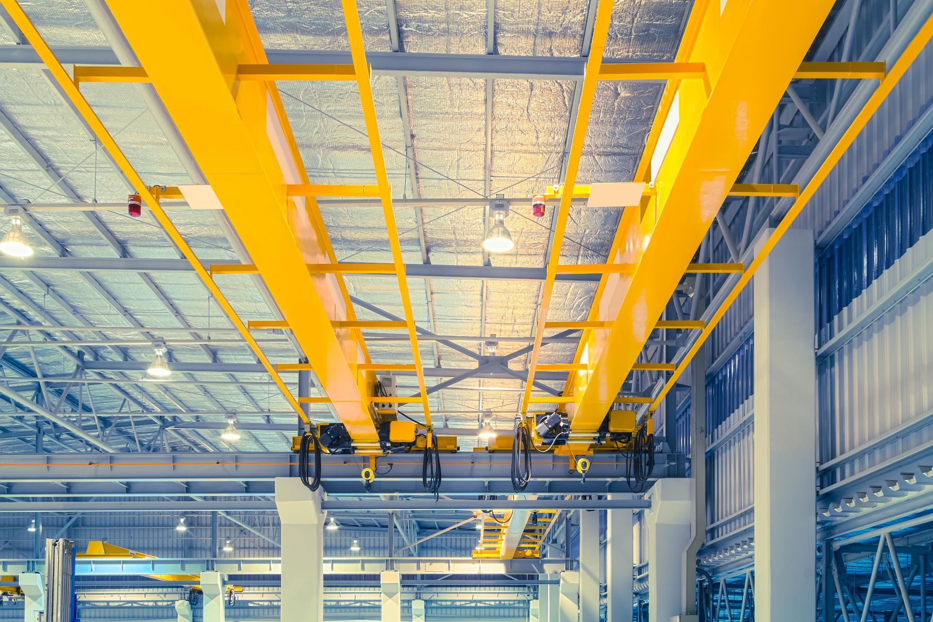 Yellow overhead crane system inside a large industrial building.