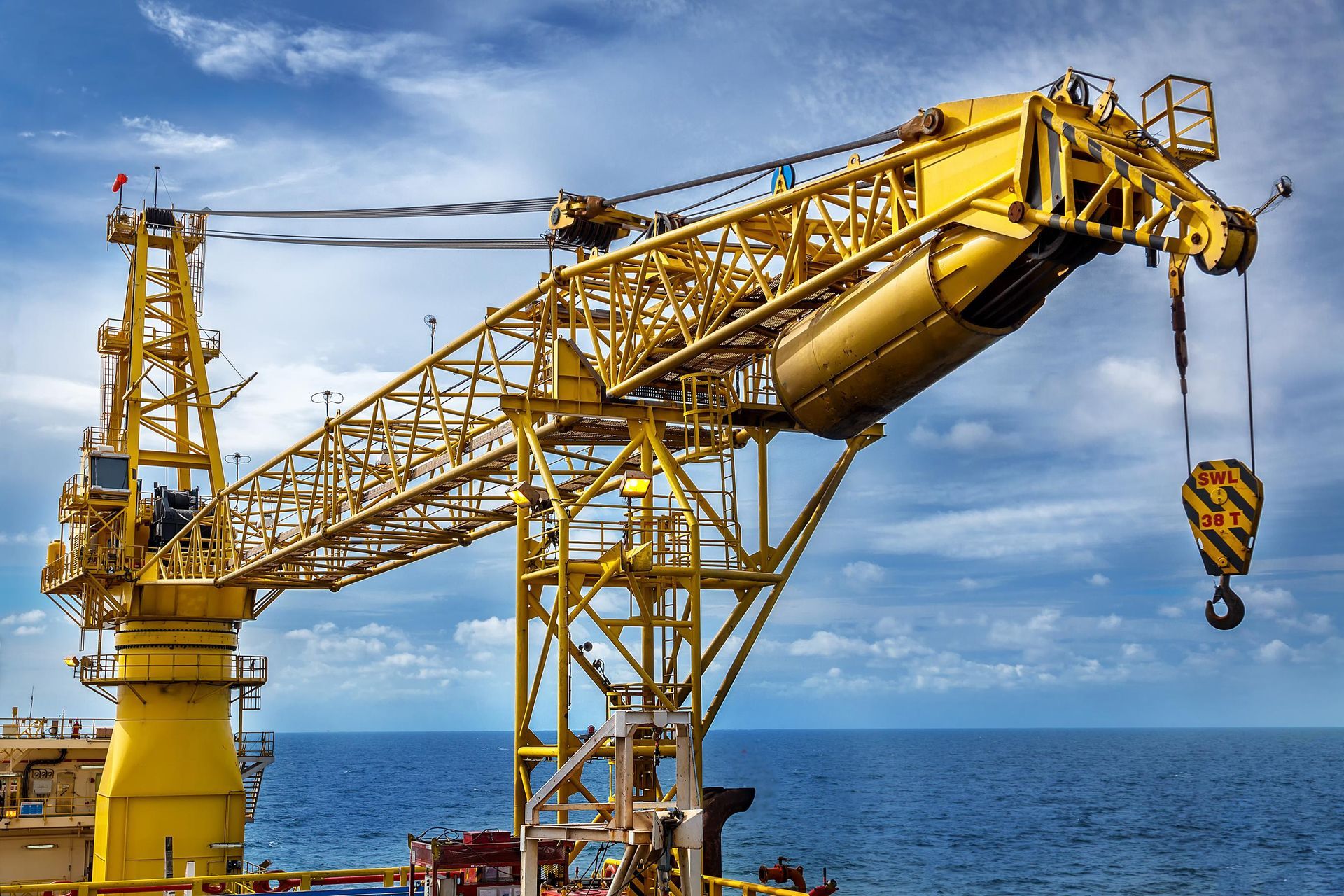 Yellow offshore crane against a blue sky and sea.