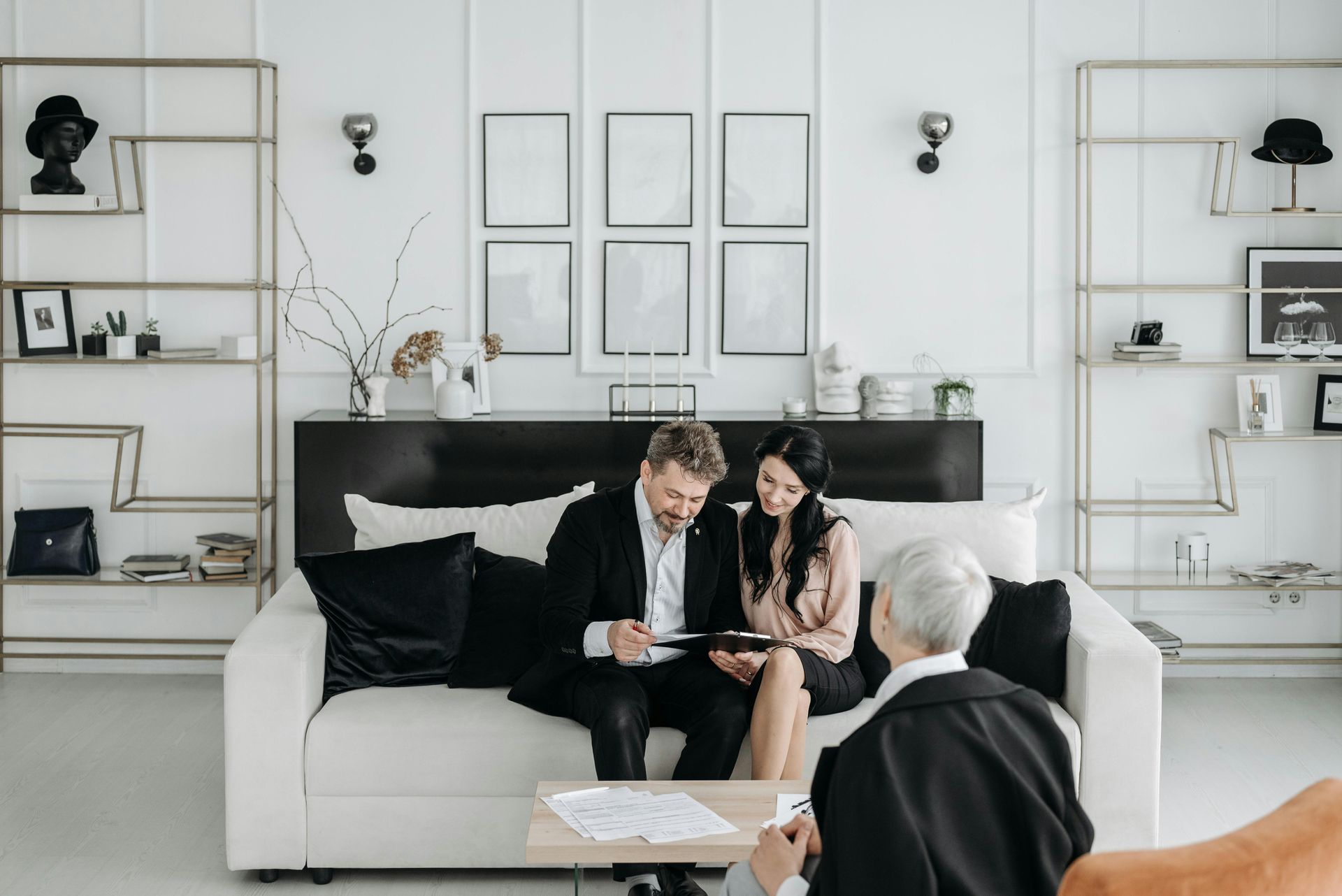 People in business attire reviewing documents on a couch, indoors.
