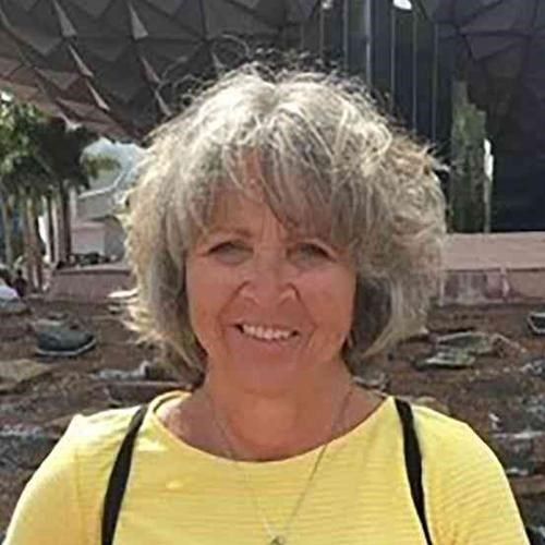 The woman is wearing a yellow shirt and smiling for the camera.