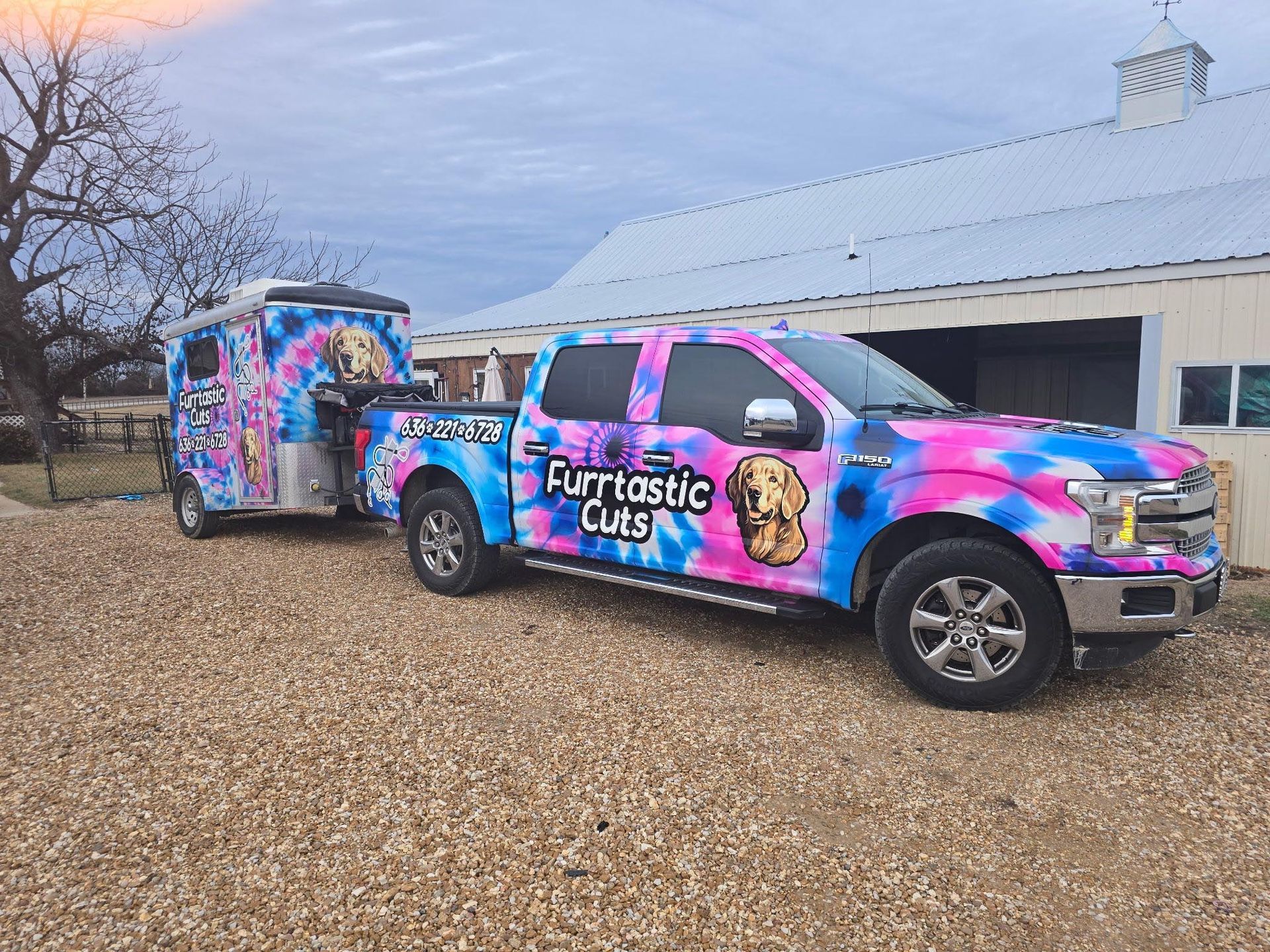 A pink and blue truck with a trailer attached to it is parked in front of a building.