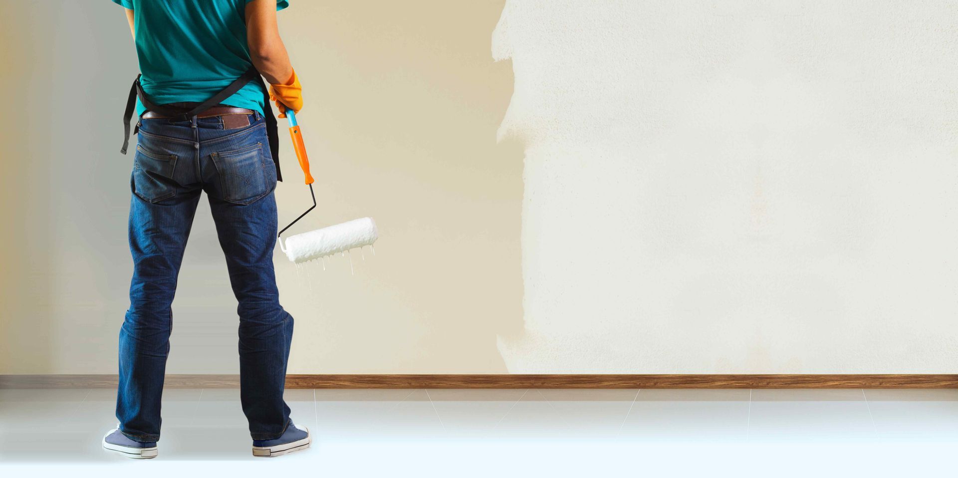 Person paints a wall white with a paint roller.