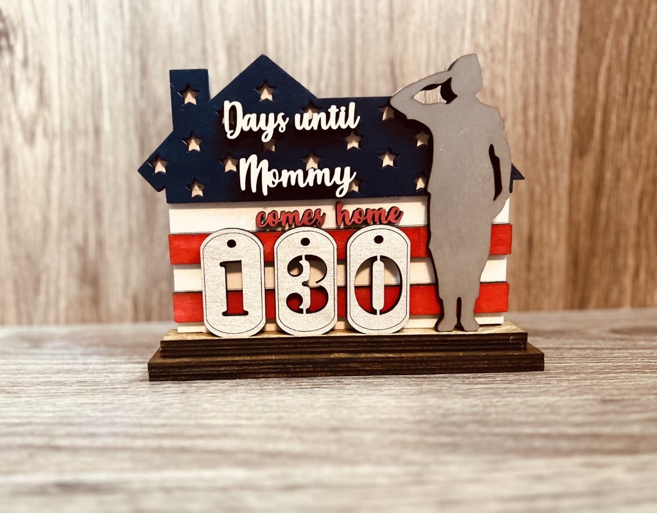 A wooden sign that says `` days until mommy '' is sitting on a wooden table.