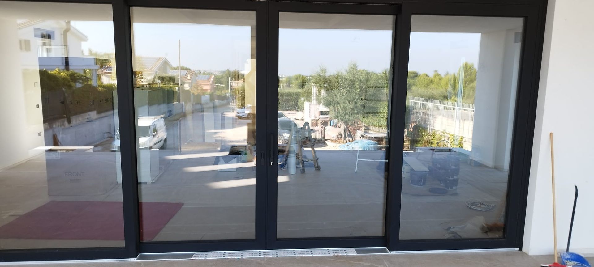 Porte a vetri che si affacciano su un patio con vista su edifici e alberi.