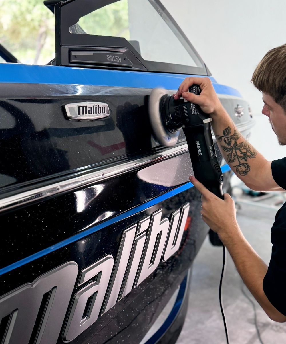 A man is polishing the side of a malibu boat