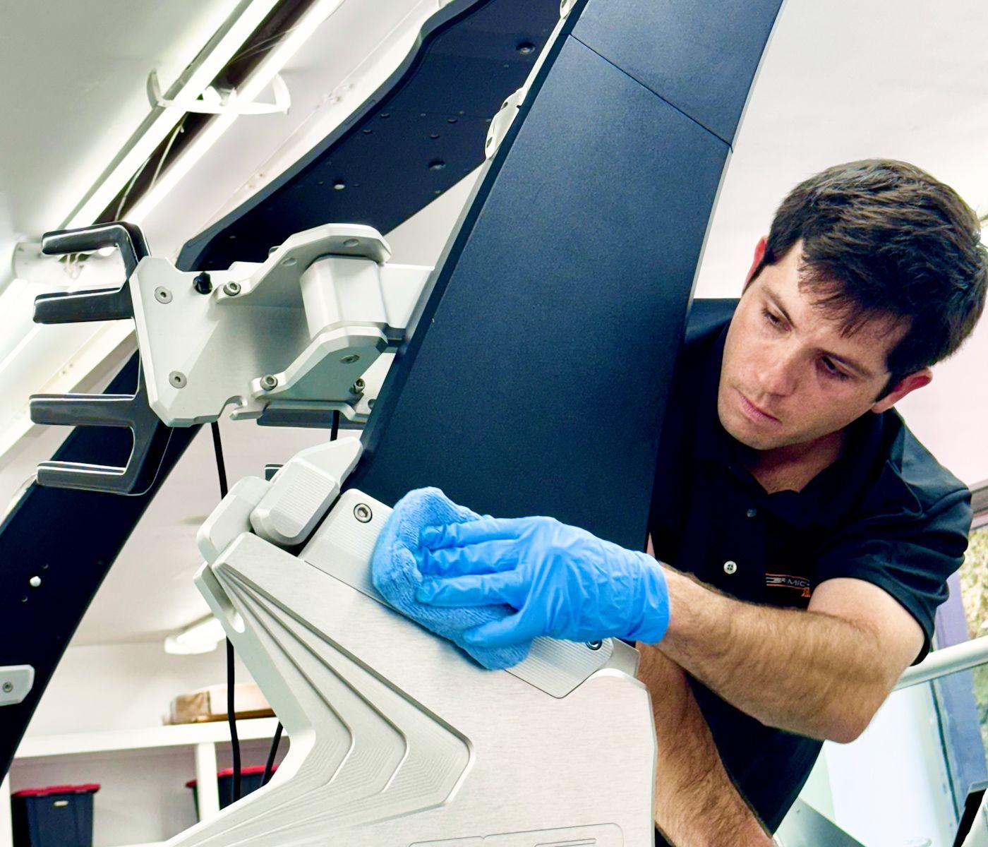 A man wearing blue gloves is working on a machine