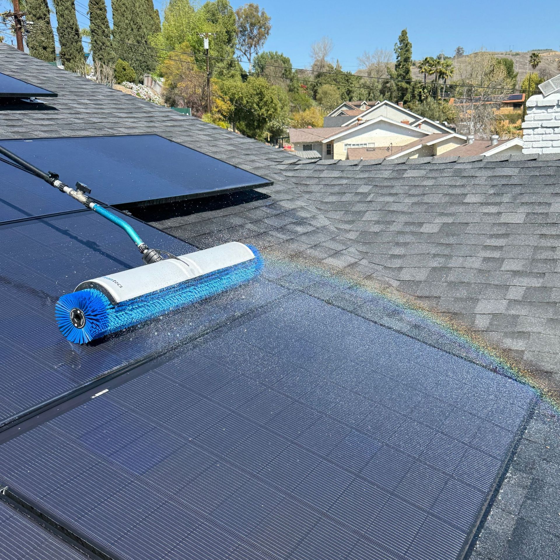 NFG Solar Panel Cleaning Company - A brush is being used to clean solar panels on a roof.