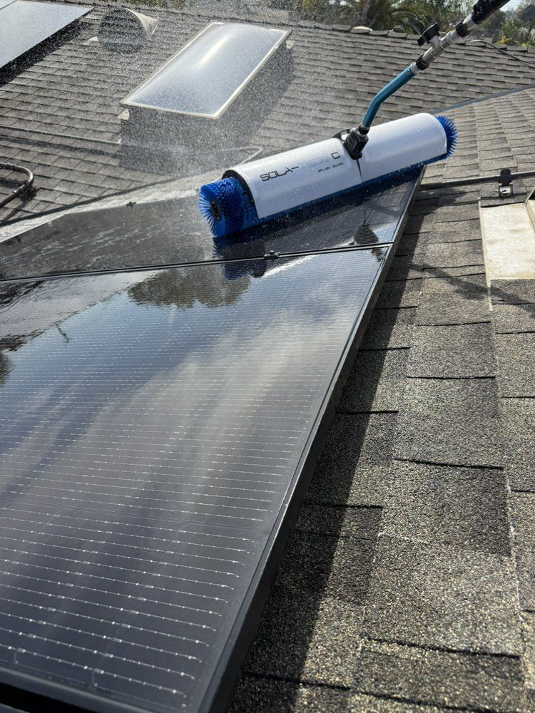 NFG Solar Panel Cleaning Company - A solar panel is being cleaned on a roof with a brush.