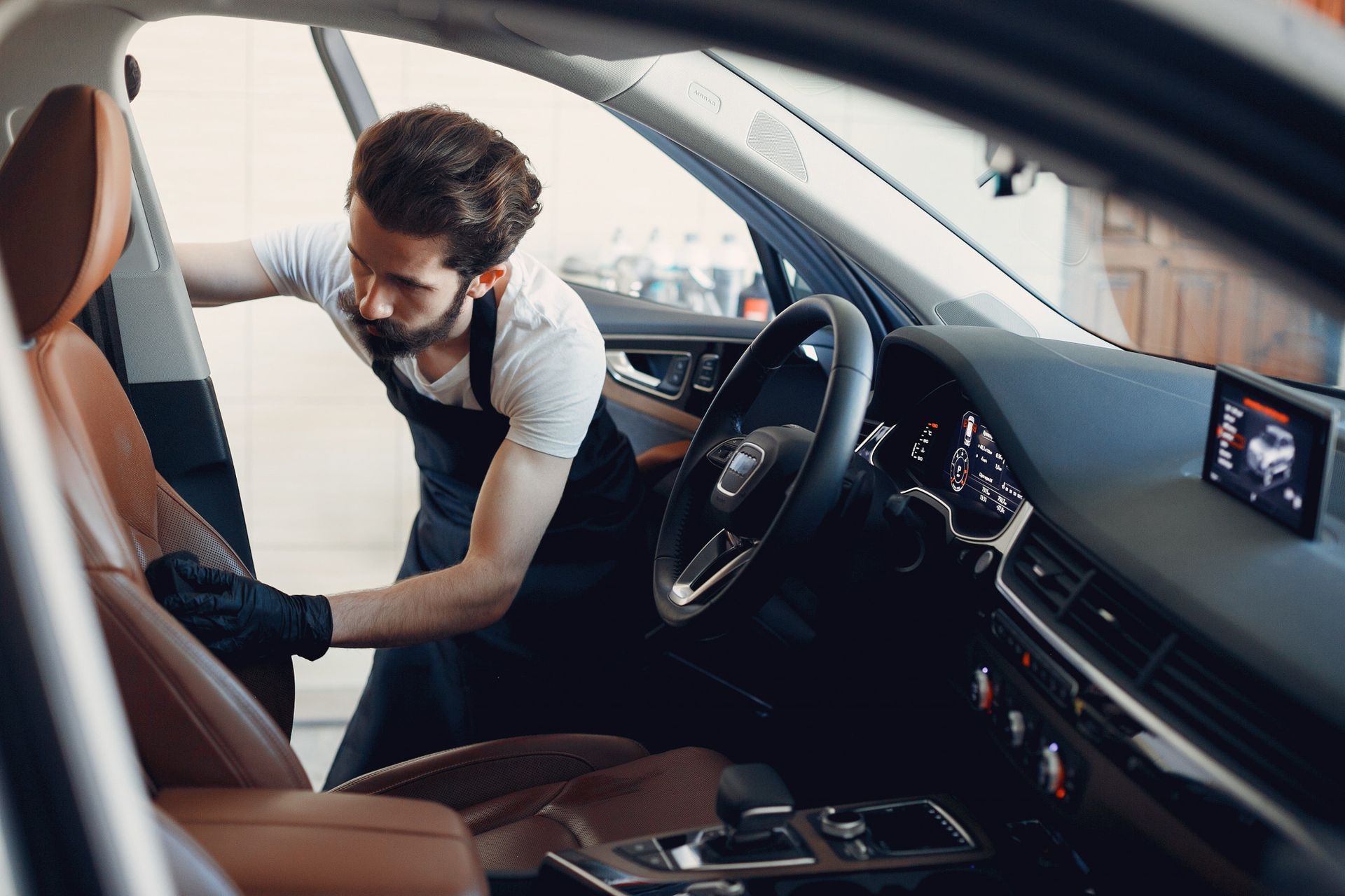 Mechanic inspecting the front seat of a car interior while leaning in from the driver’s side