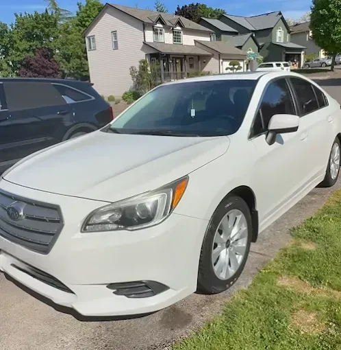 White Subaru Legacy sedan parked on a residential street.