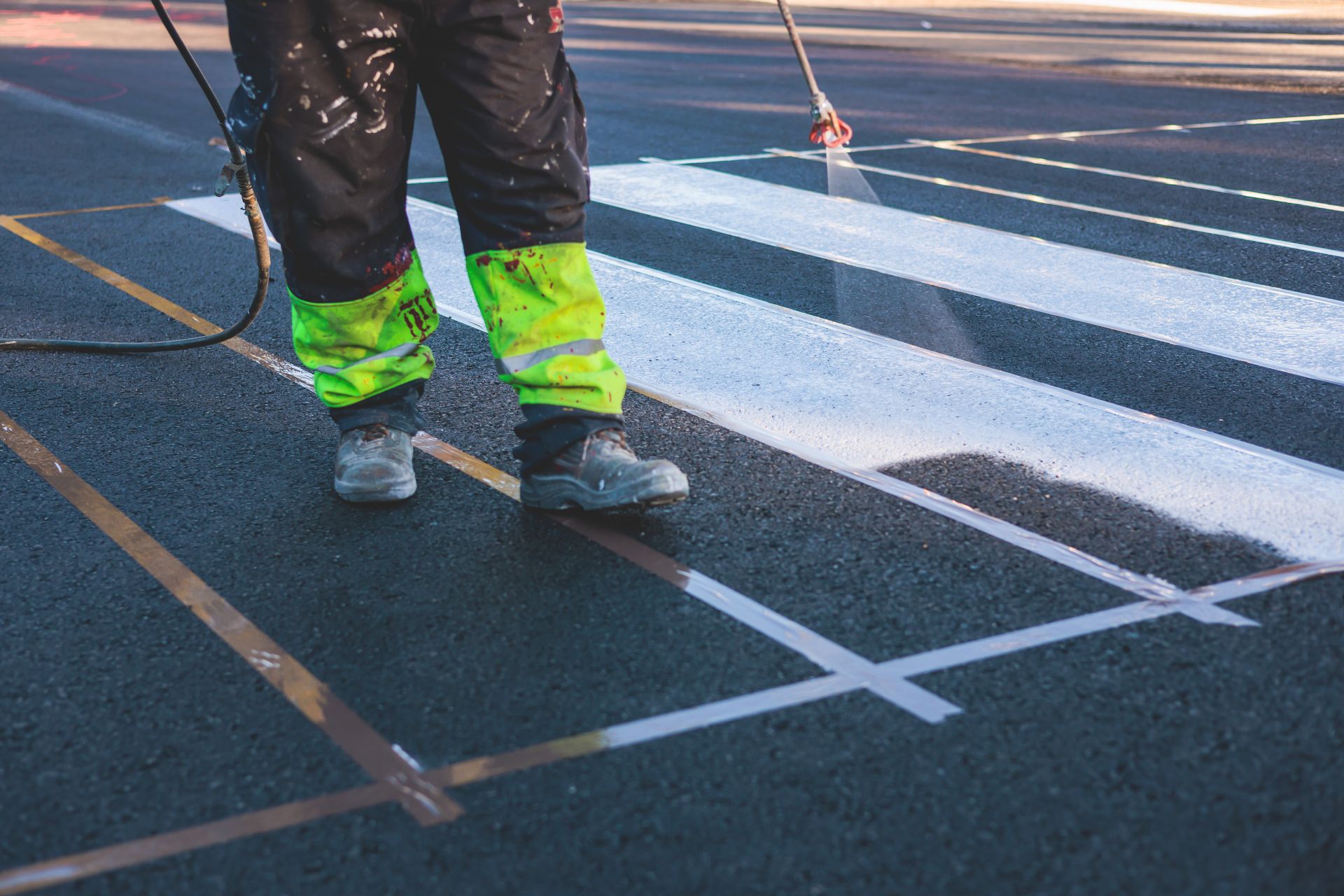 A person is painting a crosswalk on the road.