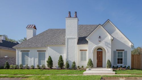 A white brick, one-story suburban home with a gray shingled roof, two prominent chimneys, and a brown front door.