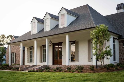 A white, single-story house with a prominent front porch, three dormer windows, and a dark shingled roof.