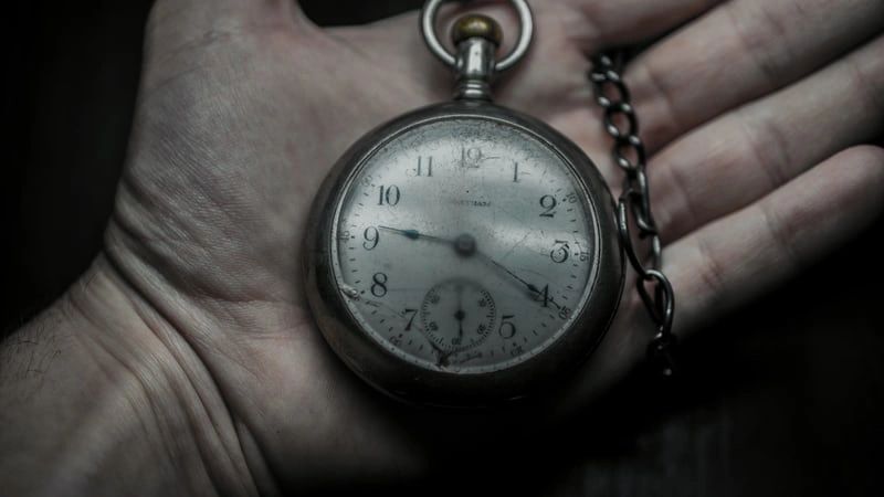 A person is holding a pocket watch in their hand.