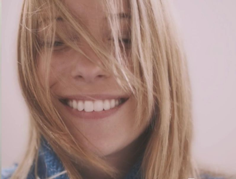 A close up of a woman smiling with her hair blowing in the wind.