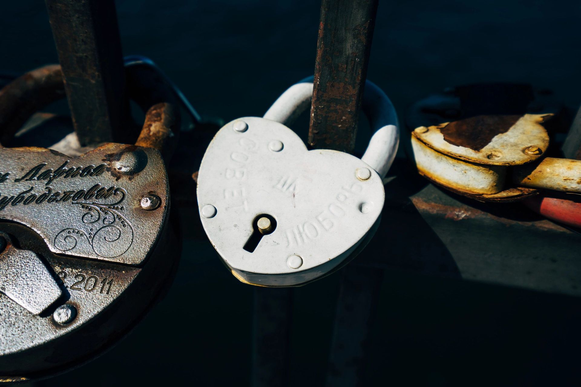 A heart shaped padlock with a key in it is hanging on a metal pole.