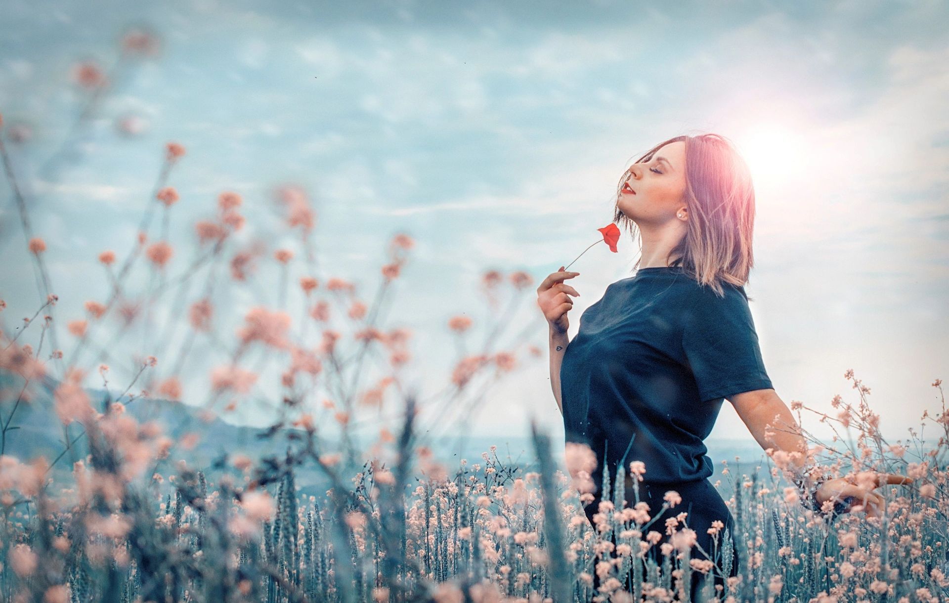 A woman is smelling a flower in a field of flowers.