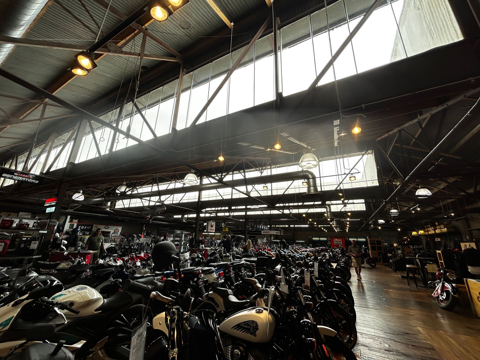 Large motorcycle showroom with rows of bikes under bright skylights and a high industrial ceiling