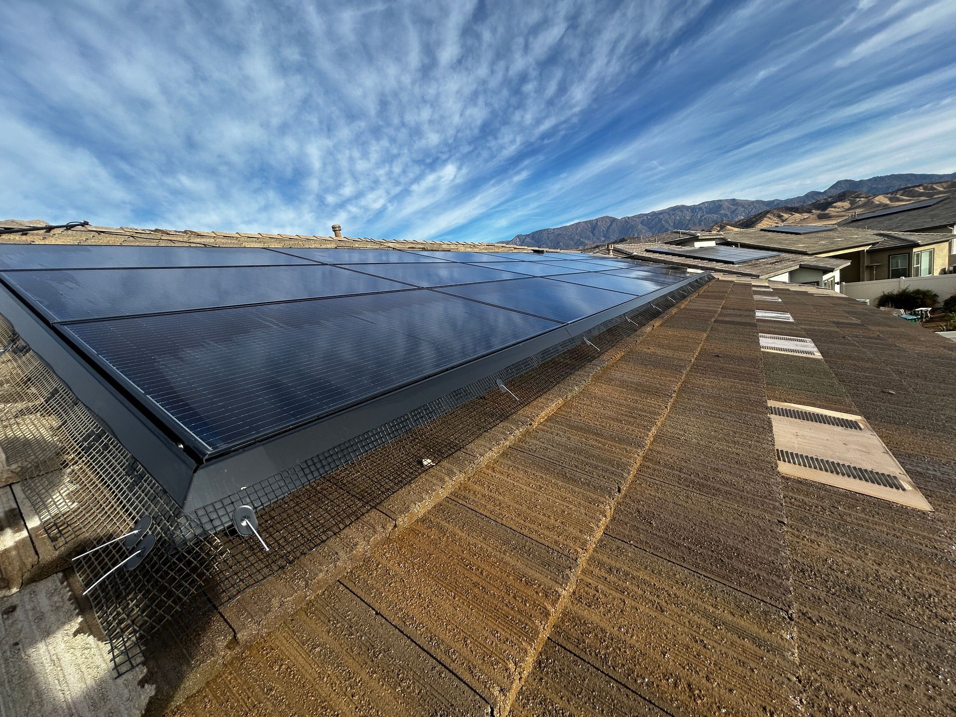 Gloved hand cleaning a solar panel outdoors on a rooftop or solar farm