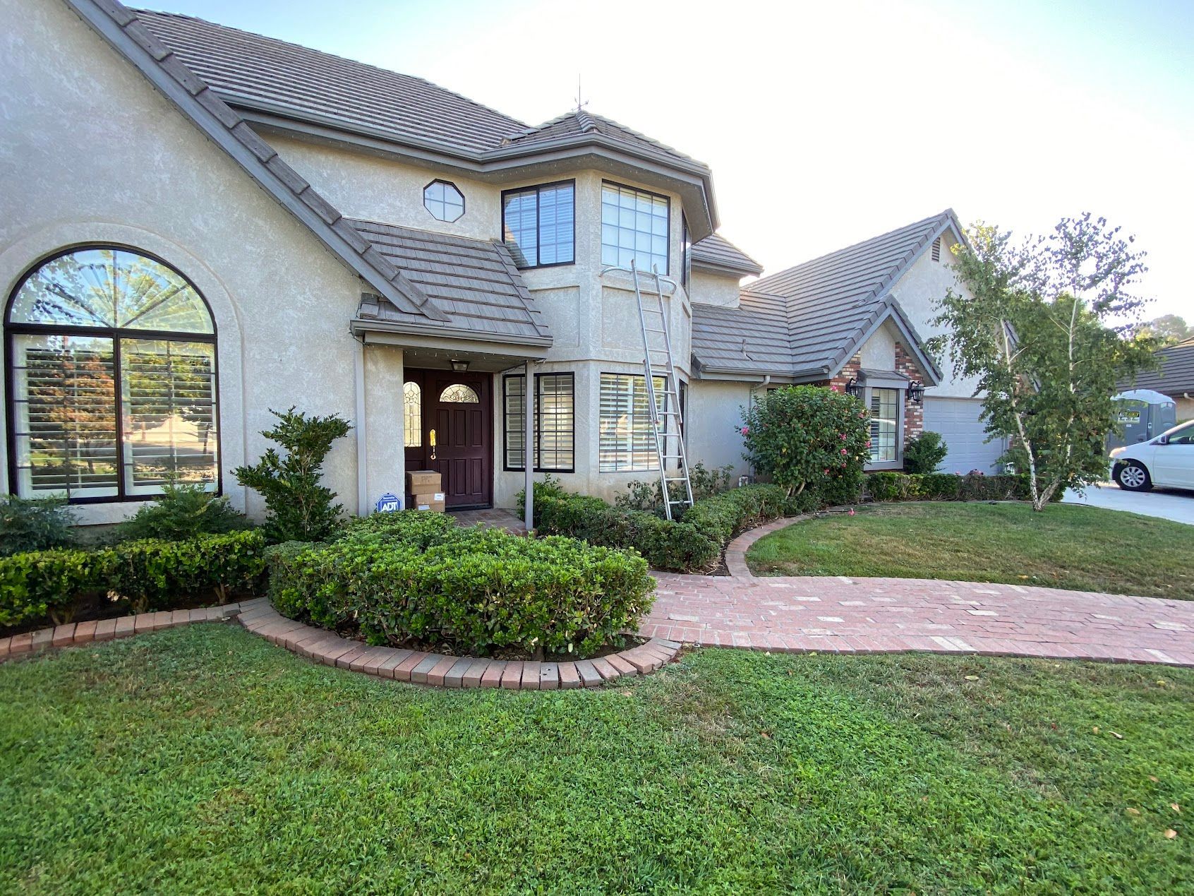 Large stucco suburban house with arched windows, a brick walkway, and a landscaped front yard