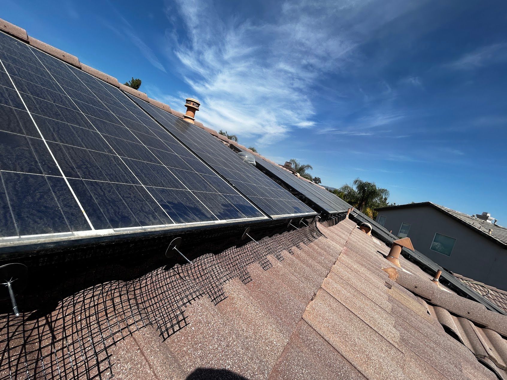 Solar panels mounted on a sloped roof under a clear blue sky