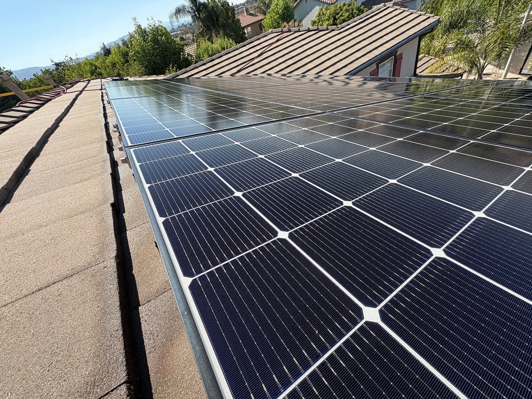 Solar panels installed on a sloped rooftop under a clear blue sky.