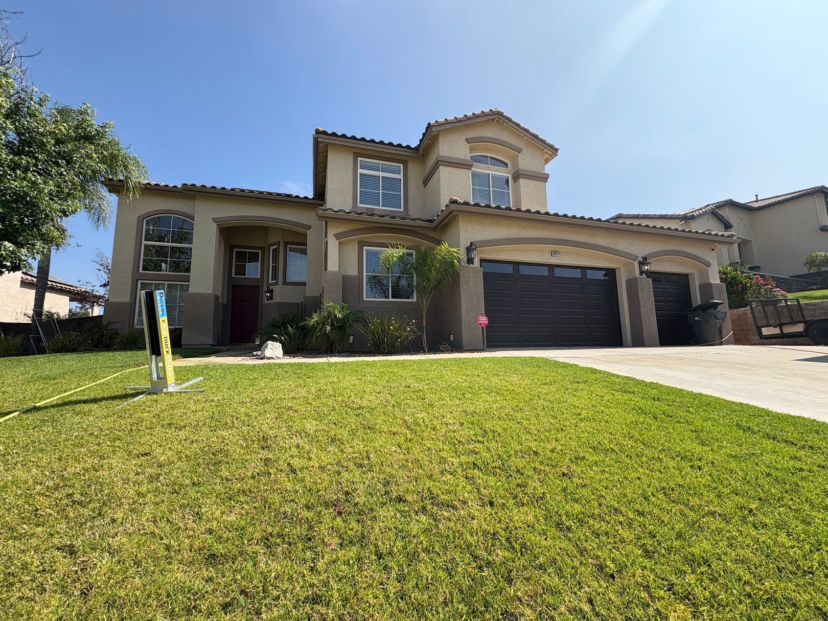 Suburban house with a large green lawn and driveway under a clear blue sky
