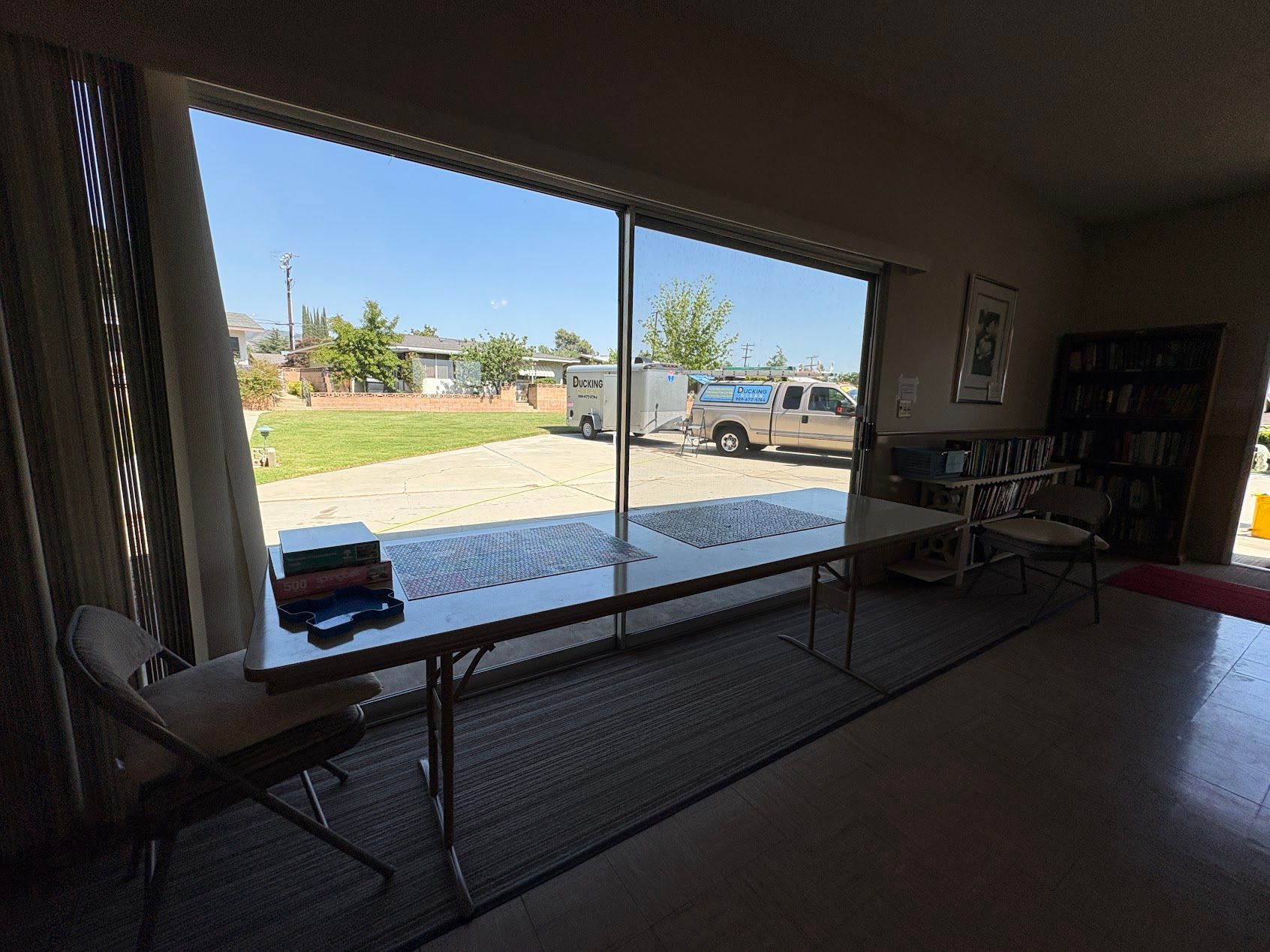Indoor room with tables facing a large open doorway to a sunny outdoor patio and parked trucks.