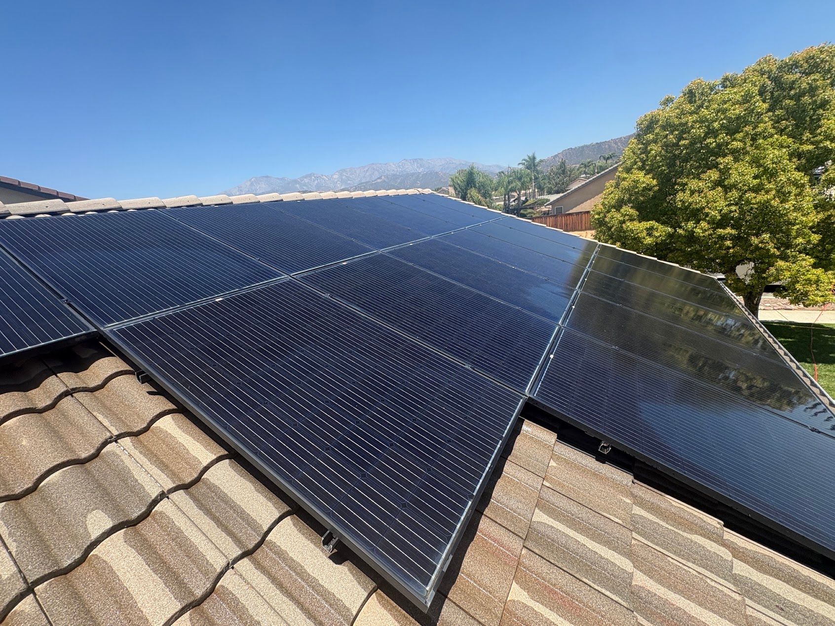 Solar panels mounted on a tiled roof under a clear blue sky