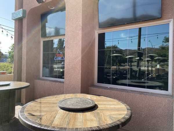 Outdoor café tables beside a stucco building with large windows in bright daylight