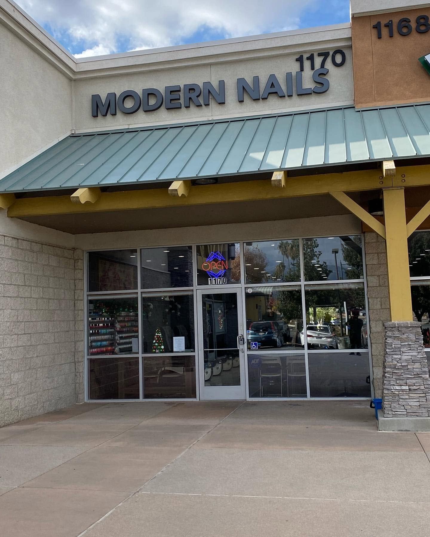 Storefront for Modern Nails with green awning and glass doors in a shopping center