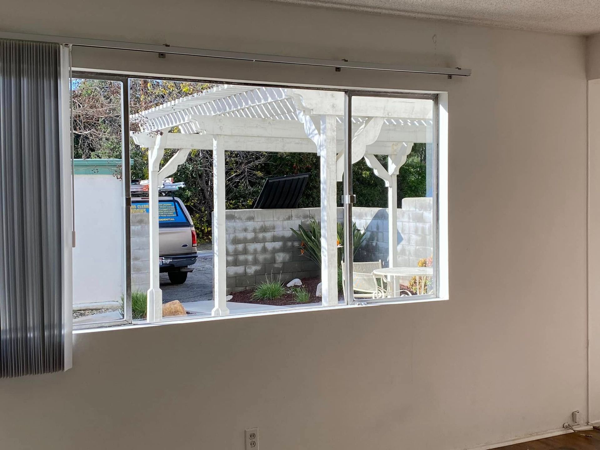 Living room with large window overlooking a patio and parked blue car outside
